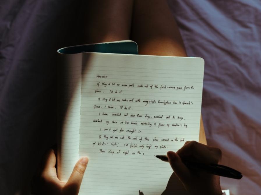 Foto af menneske, der skriver i en notesbog.